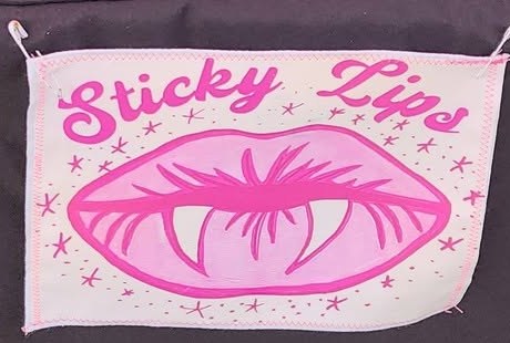 The Sticky Lips table banner: pink script and pink lips with teeth showing, surrounded by small stars